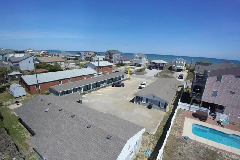Aerial view of the motel's roofline and parking lot, with the Kill Devil Hills oceanfront neighbourhood beyond