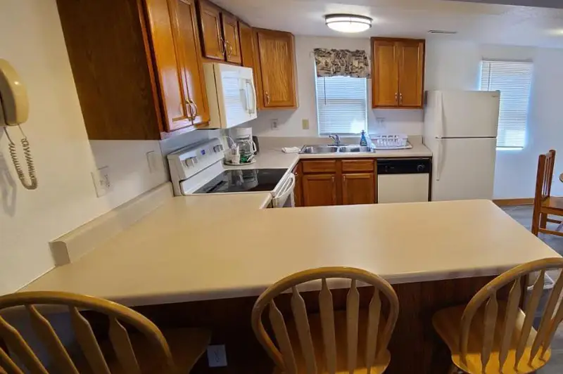 A kitchen with a full-size stove, a refrigerator and a breakfast bar with stools