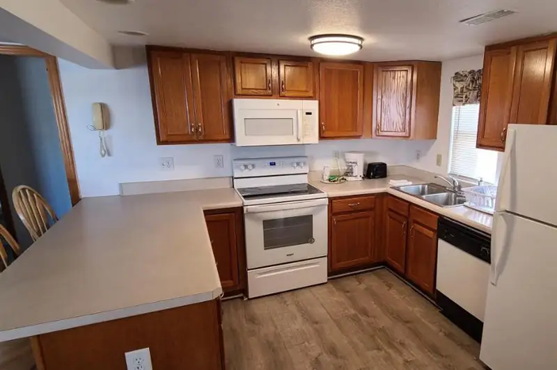 A kitchen with wood cabinets, a full-size stove, a refrigerator and a round dining table