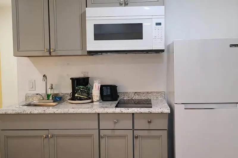 A kitchenette counter with a microwave, coffee maker and refrigerator