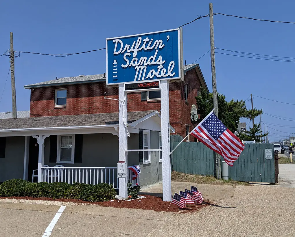 The Driftin Sands Motel pole sign and building, with American flags flying outside