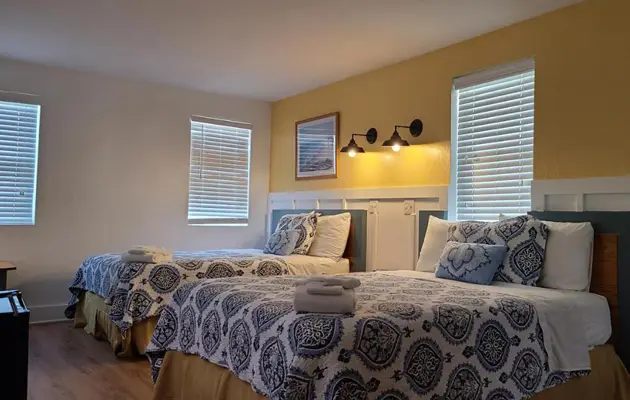 Guest room at Driftin Sands Motel with two queen beds and a bright yellow accent wall